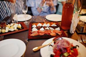 närbild av läckra köttskivor, ost, sallad och alkoholdryck på bordet på möhippa. foto