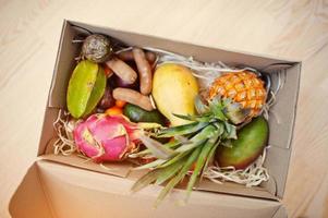 låda med exotiska frukter. hälsosam kost bantning paket. pitahaya, carambola, papaya, babyananas, mango, passionsfrukt, tamarind och annat. foto