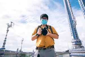 vuxen asiatisk resenärfotograf man med mask i ansiktet för ny normal utomhuslivsstil foto