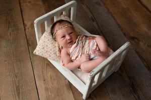 nyfödd flicka liggande på en miniatyr spjälsäng foto