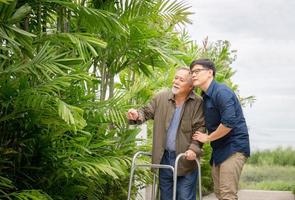 senior asiatisk far och medelålders son promenad i parken, lycka asiatisk familj koncept foto