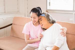 medelålders dotter och senior asiatisk mamma i vardagsrummet foto