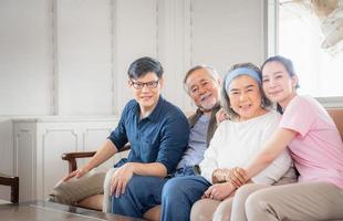 asiatisk familj sitter i vardagsrummet, äldre far mor och medelålders son och dotter, lycka familj koncept foto