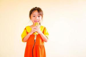 härlig baby flicka bär gul-orange outfit gokowa outfit eller mugunghwa, och hålla guld mikrofon sjunga musik. flickor och tonåring mode klänning. foto