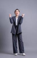 ung asiatisk affärskvinna som står på grå bakgrund foto