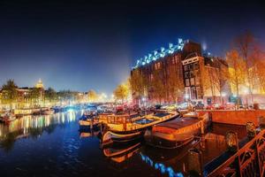 vacker natt i amsterdam. belysning av byggnader foto