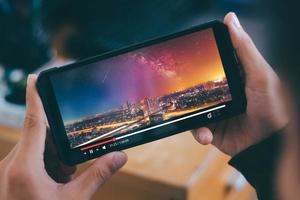 online filmström med smartphone. ung man tittar på film på mobiltelefon med imaginär videospelare tjänst. foto