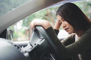 stressad och olycklig asiatisk förare som sitter inne i sitt fordon och känner sig ledsen och arg. bilolyckor orsakas av vårdslöshet. och föraren trött. berusad och sömnig kvinnlig baksmälla. foto