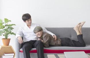 ett manligt par med en asiatisk man som sitter i en soffa med sin kärlek till varandra. foto