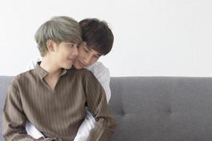 ett manligt par med en asiatisk man som gosar i soffan med sin kärlek till varandra. foto