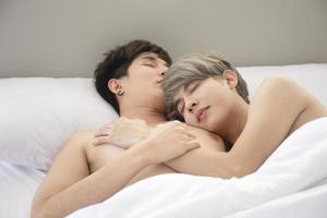 ett manligt par med en asiatisk man sover tillsammans i en säng, en symbol för sexuell mångfald, som uttrycker öppet homosexuella män som accepterar hbt-koncept. foto