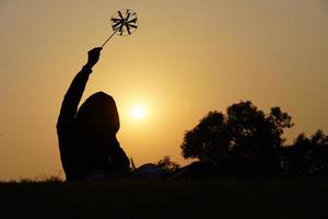 glad ung pojke med ett leksaksblad på en solnedgångsbakgrund över ett vetefält foto