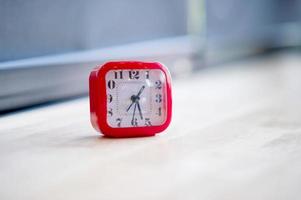 röd väckarklocka placerad på färgglada trägolv, tidskoncept foto