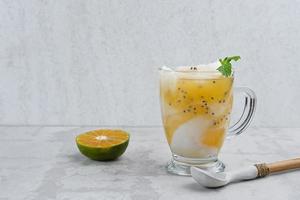es kelapa jeruk, en typisk indonesisk drink gjord på färska apelsiner pressade med riven ung kokosnöt. foto