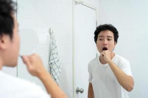 asiatisk ung man borstar tänderna. foto