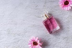 rosa parfymflaska med rosa blommor foto