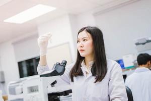 ung kvinnlig medicinsk forskare tittar på provrör i medicinskt laboratorium foto