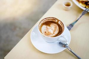 selektivt fokus, en kopp hett latte kaffe med vacker mjölkskum latte art textur på träbord. ovanifrån, kopieringsutrymme. reklam för cafémeny. kafémenyn foto