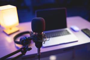 mikrofon i hemmastudio för inspelning och laptop med inspelningsprogramvara för att göra musik nattljus. musikproduktion koncept. foto