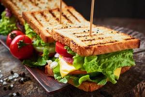 hemlagad smörgås med skinka, sallad, ost och tomat på en träbakgrund foto