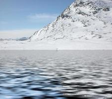 berg med snö som reflekteras i sjövatten foto