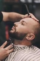 porträtt av en skäggig man hipster i en barbershop foto