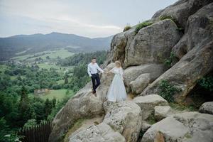 fotografering av ett förälskat par i bergen. flickan är klädd som en brud i en bröllopsklänning. foto