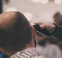 frisör klipper håret på en ung man foto