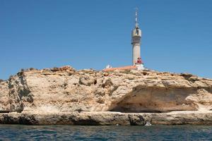 Portugals kust. klippor vid algarve, enorm kommunikationsantenn och fyr. foto