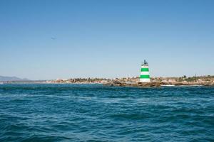 vackra atlantkusten nära portimao, algarve. fyr med gröna och vita ränder. portugal foto