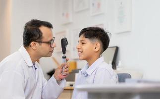 leende indisk pojke gör ögontest kontrollera undersökning med optiker i optisk butik foto