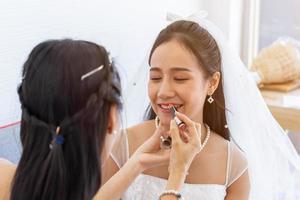 en kvinnlig artist är makeup för asiatiska brudar för hennes bröllop. foto