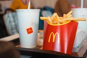 pommes frites med en röd ask med mcdonalds logotyp på en bricka och en drink. snabbmatsrestaurangskedjor. Ryssland, Kaluga, 21 mars 2022. foto