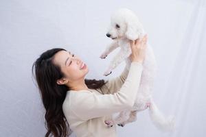 ung asiatisk kvinna kramar sin hund på vit bakgrund foto