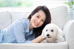 ung asiatisk kvinna som leker med hund hemma foto