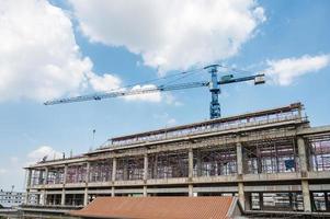 struktur av stor byggnad med arbetare som arbetar, kran och ställning på byggarbetsplatsen foto