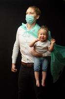 pappa i en medicinsk mask håller sin lilla dotter. konceptet att skydda barn under epidemin av coronavirus foto