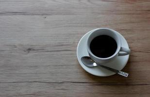 kaffe i vit kopp på träbord i café med belysning bakgrund foto