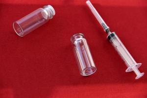 medicinska spruta tabletter och glas bubblor på en röd bakgrund foto