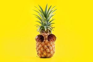 kreativ ananas tittar upp med solglasögon och skal isolerad på gul bakgrund, designmönster för sommarsemesterstrandidé, kopieringsutrymme närbild foto