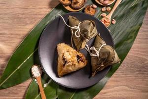 zongzi, ångade risdumplings på träbord bambublad, mat i drakbåtsfestival duanwu koncept, närbild, kopieringsutrymme, ovanifrån, platt lay foto