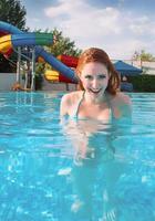 porträtt av leende ung vacker rödhårig kvinna i solig dag i öppen pool på sommaren foto