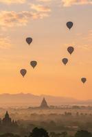grupp av luftballonger som flyger över forntida pagod i bagan slätt i gryningen. Bagan är nu UNESCOs världsarv och Myanmars första kungarike. foto