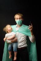 pappa i en medicinsk mask håller sin lilla dotter. konceptet att skydda barn under epidemin av coronavirus foto