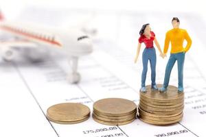 miniatyr par människor och stapla mynt på statement och flygplanet bakom. sparande och lånekoncept. foto