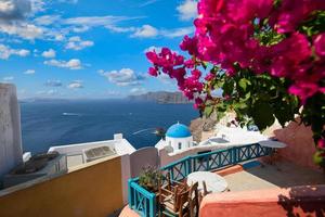 sommarsemester panorama, lyx berömda europa destination. vit arkitektur i Santorini, Grekland. perfekt reselandskap med rosa blommor och kryssningsfartyg i solljus och blå himmel. fantastisk utsikt foto