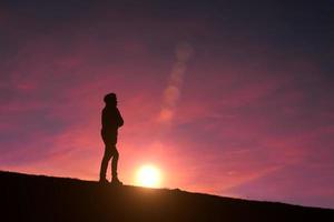 vuxen man siluett i berget med en romantisk solnedgång bakgrund foto