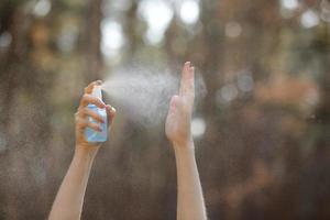 kvinnans hand trycker alkoholspray i naturen för att rengöra hennes hand. alkoholspray är mycket viktigt i det dagliga livet. myggmedel eller antiseptisk foto