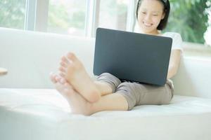 leende glad kvinna sitter i soffan och använder laptop - hög vinkelvy foto