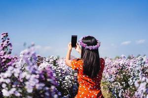 resa kvinna koppla av i margaret blomma fält med smartphone. foto